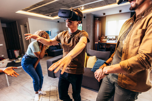 Cheerful friends having fun with VR in home interior - Foto, immagini
