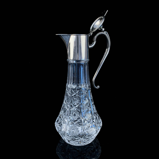 antique crystal decanter with silver neck. vintage drink decanter on black isolated background - Fotó, kép