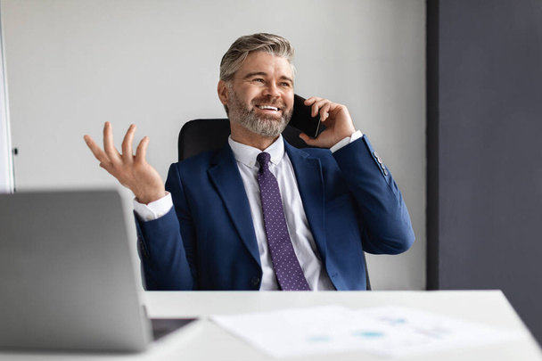 Obchodní sdělení. Usmívající se starší muž podnikatelské mluvení na mobilním telefonu v kanceláři - Fotografie, Obrázek