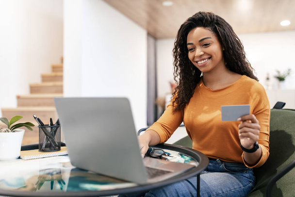 Femme heureuse tenant carte de crédit de débit, en utilisant l'ordinateur - Photo, image