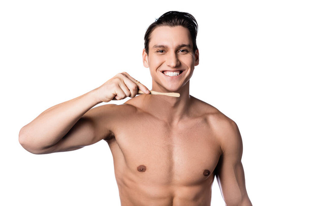 веселий без сорочки чоловік тримає зубну щітку і дивиться на камеру ізольовано на білому
 - Фото, зображення