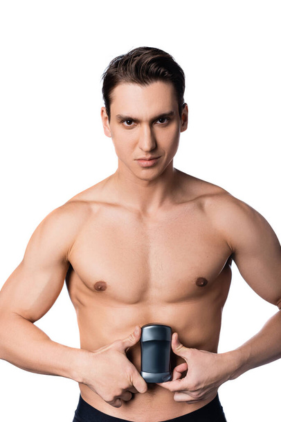 homme torse nu avec corps musculaire tenant déodorant sec et regardant la caméra isolée sur blanc - Photo, image