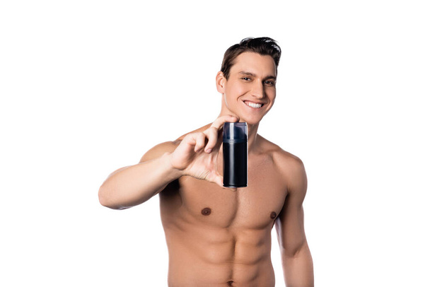 feliz hombre sin camisa mostrando antitranspirante en la cámara aislado en blanco - Foto, Imagen