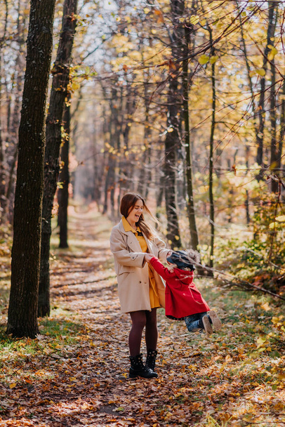 Mom and daughter play in an autumn forest - Фото, изображение