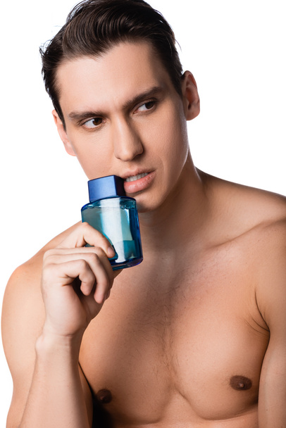 man with bare chest holding vial of perfume and looking away isolated on white - Fotó, kép
