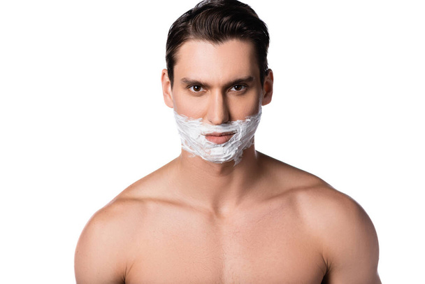 brunette man with naked shoulders and shaving foam on face looking at camera isolated on white - Fotoğraf, Görsel