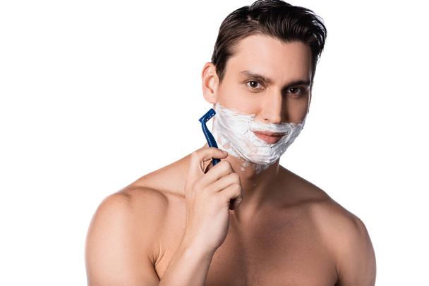 bruneta muž s holými rameny při pohledu na kameru při holení izolované na bílém - Fotografie, Obrázek