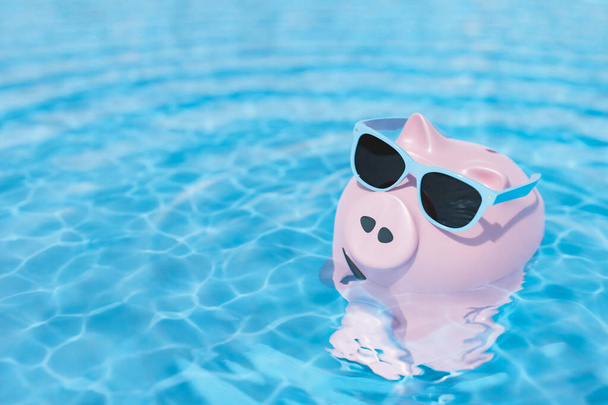 High angle 3d rendering of trendy sunglasses on pink piggy bank floating in rippling water of swimming pool in sunlight - Photo, Image