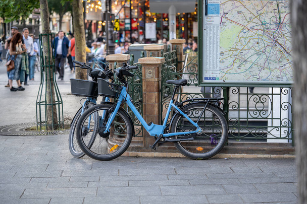 Şehrin haritasının yanındaki Paris caddesinde kiralık mavi bir bisiklet.. - Fotoğraf, Görsel