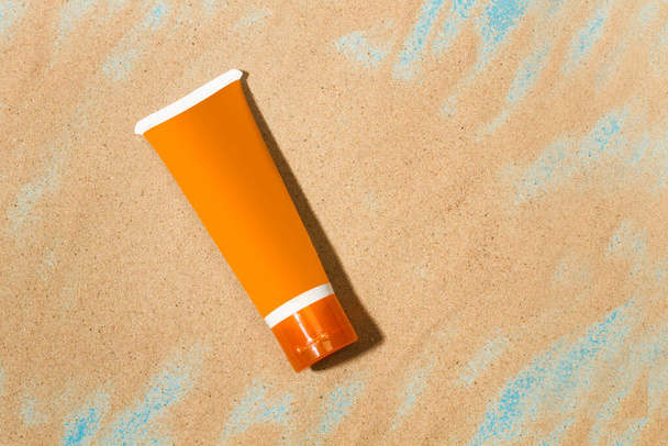 An orange suntan lotion on the sand with copy space - Foto, imagen