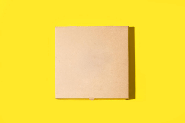 Brązowe kartonowe pudełko po pizzy na żółtym tle z przestrzenią do kopiowania - Zdjęcie, obraz