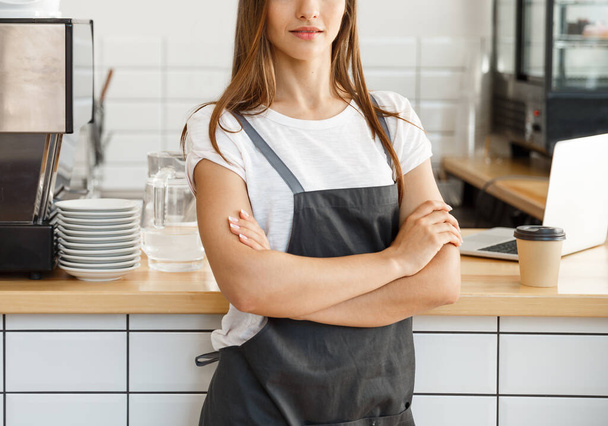 Café Business proprietário Conceito - atraente jovem bela barista caucasiano no avental com confiante olhando para a câmera no balcão da cafetaria
. - Foto, Imagem