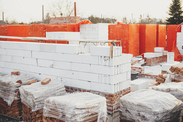 Autoclaved aerated blocks on concrete foundation, process of house building. Stacks of white aerated blocks for laying on concrete foundation. Building materials at construction site - Foto, afbeelding