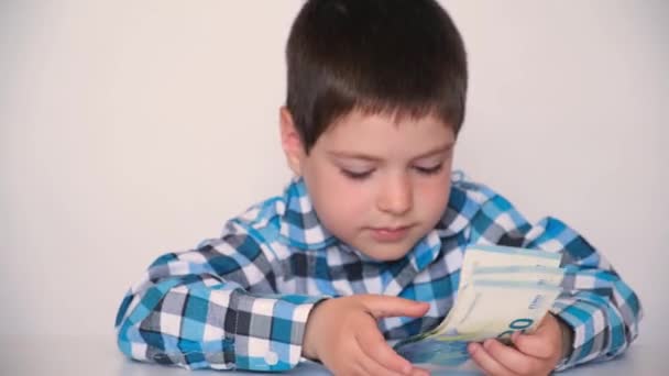 A 4-year-old boy counts money, holds euros in his hands. Teaching children financial literacy, pocket money. - Materiaali, video
