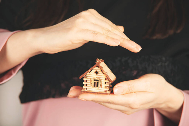 donna mano tenendo modello di casa in legno su sfondo grigio - Foto, immagini