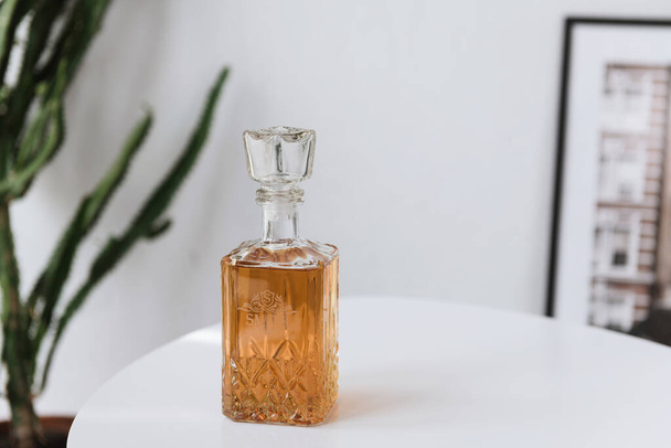carafe en verre avec whisky se tient sur une table blanche sur un fond blanc - Photo, image