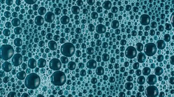 Visão de close-up de bolhas de sabão em um estouro líquido azul. Fundo abstrato do sabão - Filmagem, Vídeo