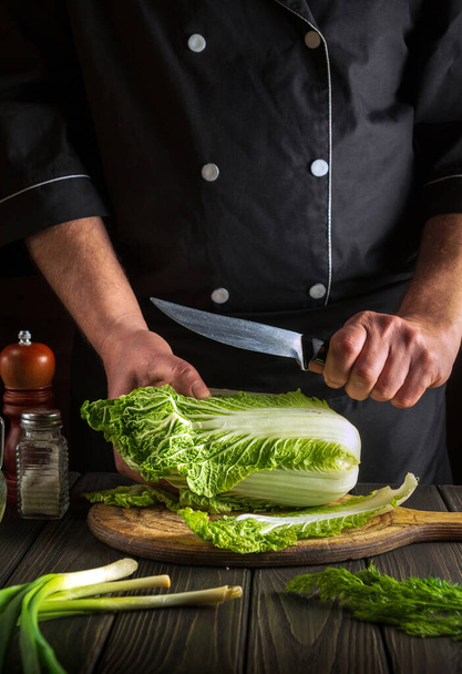 The chef prepares Napa cabbage salad. Cook while working in the restaurant kitchen. Diet breakfast or dinner idea - Foto, imagen
