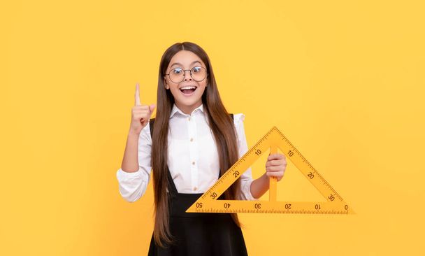 Вдохновленная идеей девочка-подросток держит треугольник. обратно в школу. алгебра и геометрия. - Фото, изображение