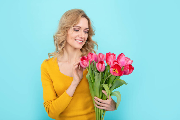 szczęśliwa młoda kobieta z wiosennym tulipanem na niebieskim tle - Zdjęcie, obraz