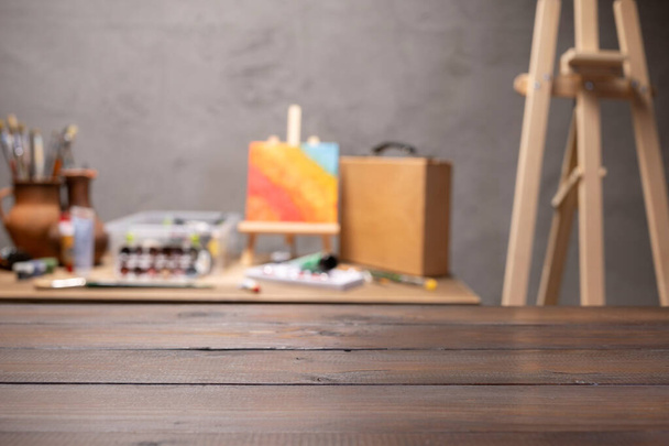 Empty front view of wood table and artist tools. Paintbrush and art painter supplies on desk background texture. Painting in artist workplace - 写真・画像