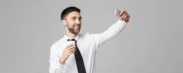 Estilo de vida y concepto de negocio - Retrato de un hombre de negocios guapo disfrutar de tomar una selfie con tomar una taza de café. Fondo blanco aislado. Copiar espacio
. - Foto, Imagen