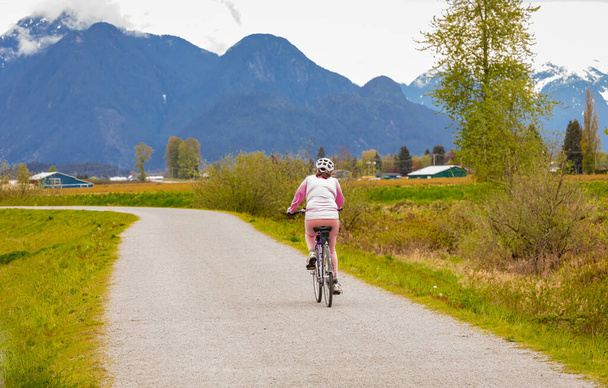 Mujer mayor montando bicicleta en el parque de verano. Vejez activa, personas y concepto de estilo de vida. Enfoque selectivo, foto de calle - Foto, Imagen