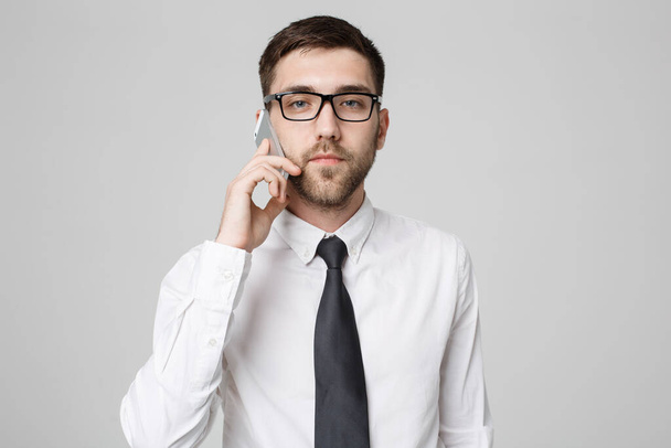 Business Concept - Portrait young handsome angry business man in suit talking on phone looking at camera. White background. - Photo, Image