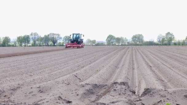 Farmer in tractor plowing a field in spring. Side view of the red farm machine with equipment. - Footage, Video