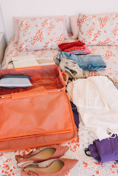 Avaa matkalaukku kaikki matkatavarat valmiina matkaa sängylle. Nainen pakkaamassa uutta matkaa varten. pystysuora. - Valokuva, kuva