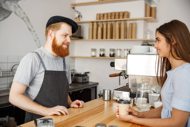 Coffee Business Concept - young beared handsome barista talking with beautiful caucasian customer in modern coffee shop. - Photo, Image