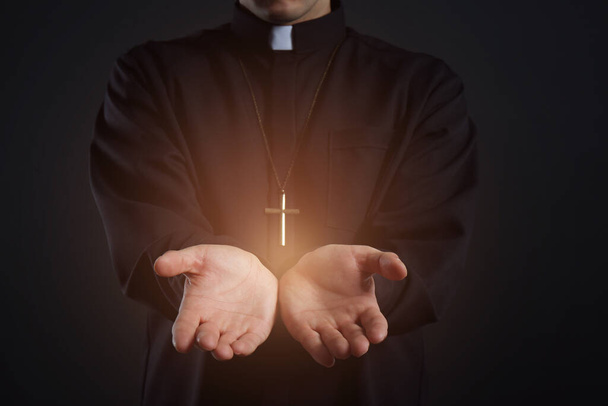 Priest reaching out his hands with holy light on black background, closeup - Fotoğraf, Görsel