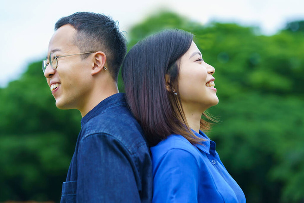 Ein junges Paar steht lächelnd Rücken an Rücken - Foto, Bild