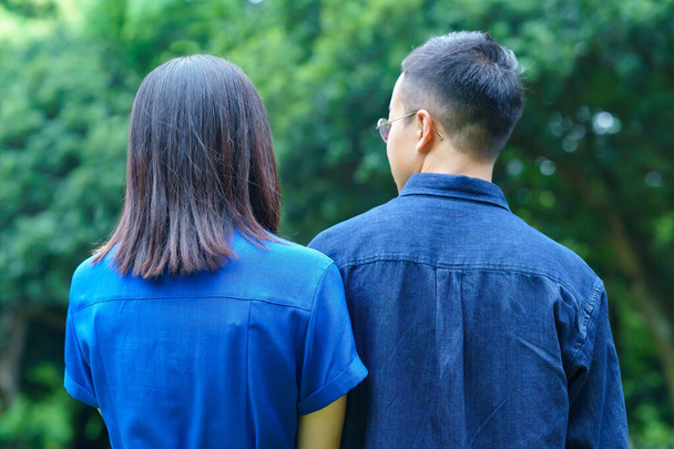 Vue arrière d'un jeune couple faisant une promenade dans un parc verdoyant - Photo, image