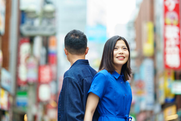 Un jeune couple debout dos à dos avec un sourire dans la ville - Photo, image
