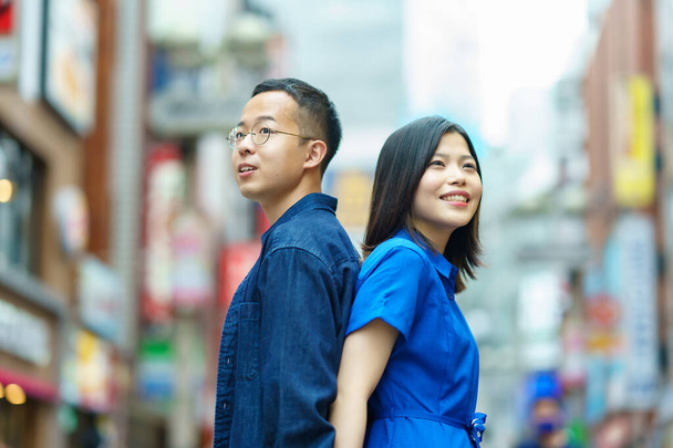 A young couple standing back to back with a smile in the city - Foto, immagini