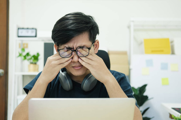 Kimerült üzletember dörzsöli a szemét, miközben otthon dolgozik... - Fotó, kép