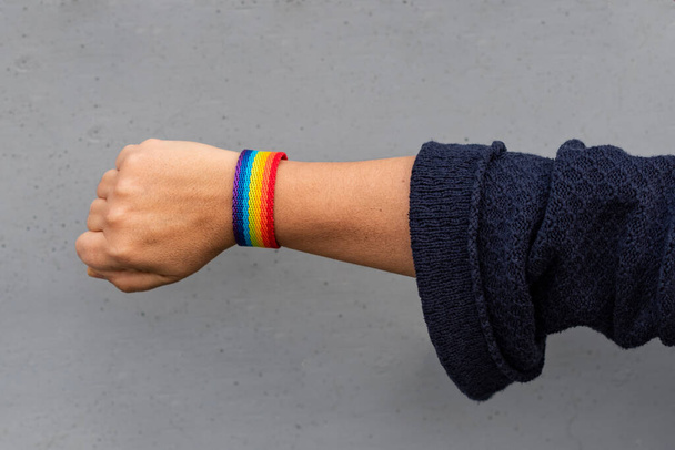 Close-up van een vrouw arm met een LGBTQ regenboog armband, concept van gay pride maand, lesbische trots, LGBT bewustwording beweging, niet-binaire inclusiviteit, en diversiteit - Foto, afbeelding