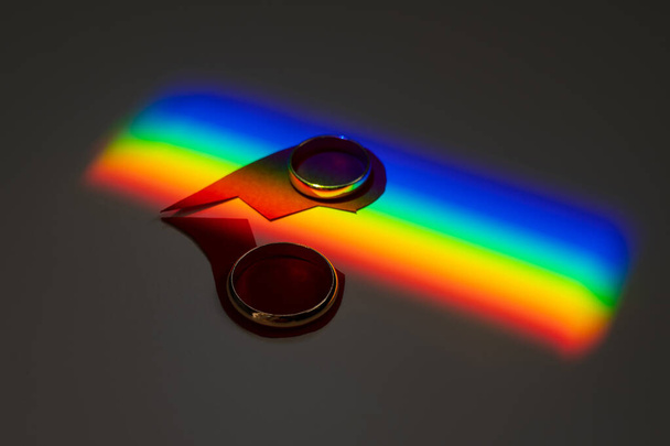 Rainbow beam on wedding rings with a broken heart. lgbt flag.  - Foto, Bild