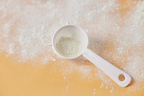 Flour and strainer on pastel orange background. Copy space. - Photo, image