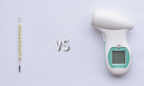 Vergelijking tussen kwikglazen thermometer en contactloze infrarood voorhoofd digitale thermometer. geïsoleerd op wit. - Foto, afbeelding