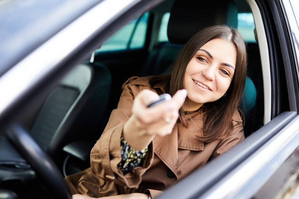 Женская рука открывает машину с дистанционным ключом от машины на парковке
. - Фото, изображение