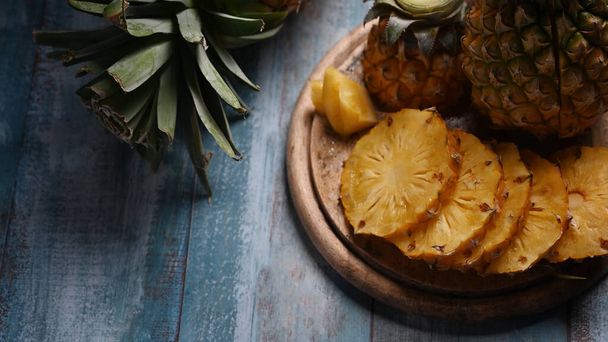 Ganze und in Scheiben geschnittene tropische Ananas auf einem Holztisch. Draufsicht, tropische Früchte, Sommerkonzept - Foto, Bild