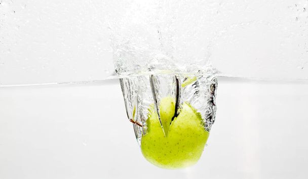 Fotografía de alta velocidad de una manzana entrando en un estanque de agua - Foto, imagen