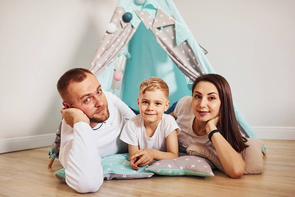 Otec, matka a jejich syn leží doma na podlaze u stanu.. - Fotografie, Obrázek