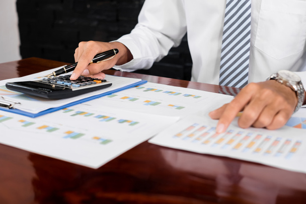 The businessman hand sits at their desks and calculates financial graphs showing the results of their investments planning the process of successful business growth. - Photo, Image