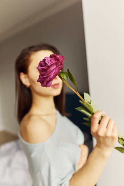 Holding flowers. Young woman resting and spending weekend at home alone at home. - Foto, Imagen