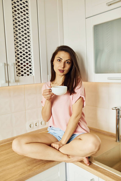 On the kitchen. Young woman resting and spending weekend at home alone at home. - Foto, afbeelding