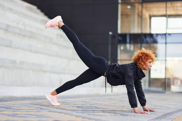 Young european redhead woman in sportive clothes doing fitness outdoors. - Fotoğraf, Görsel