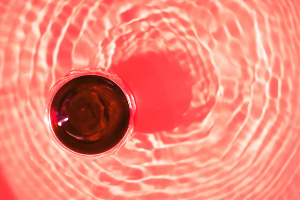Vista superior de cristal o vino tinto con fondo rojo abstracto. - Foto, Imagen
